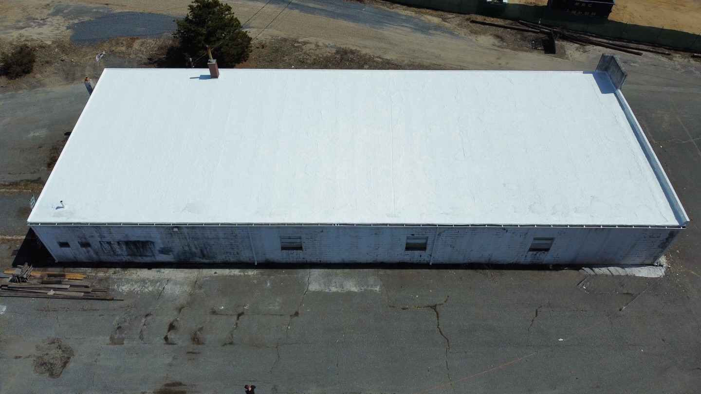 Aerial view of a large commercial building with a freshly coated white roof