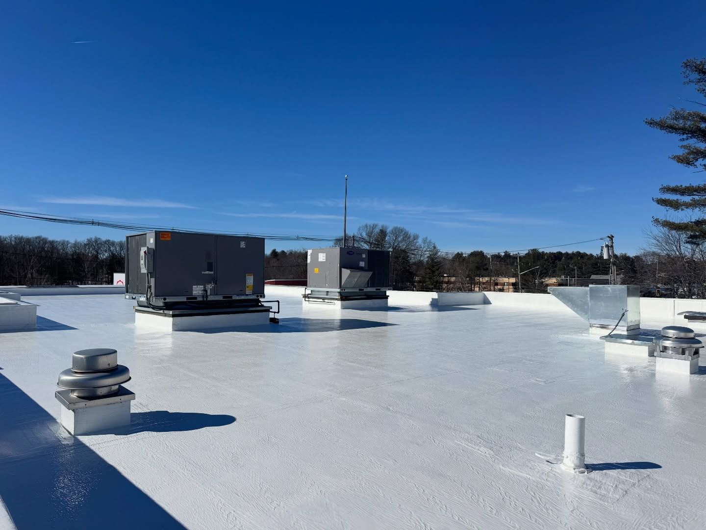 White reflective roof coating around HVAC units on a flat commercial roof