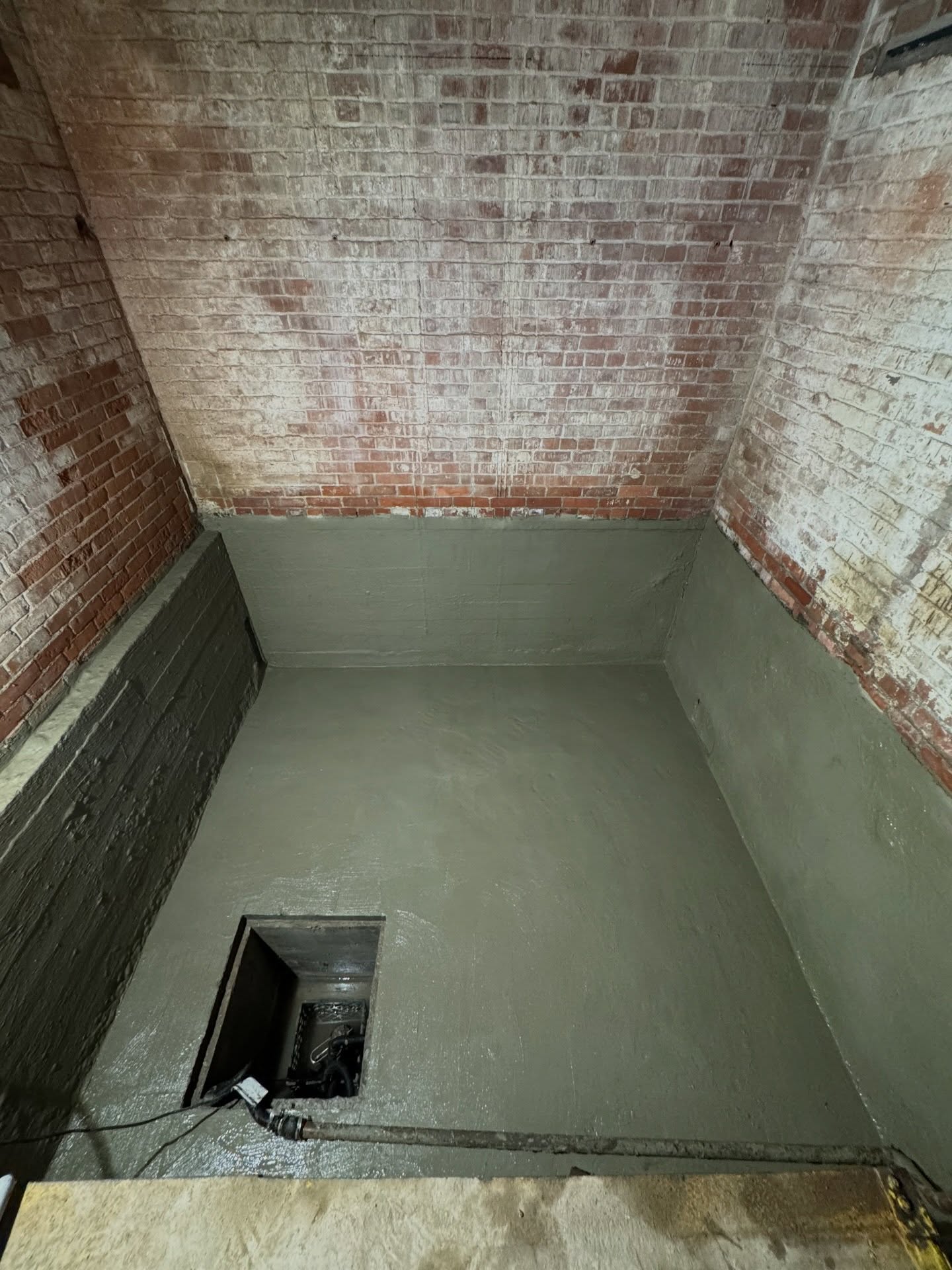 Bare basement with brick and concrete walls before waterproofing work